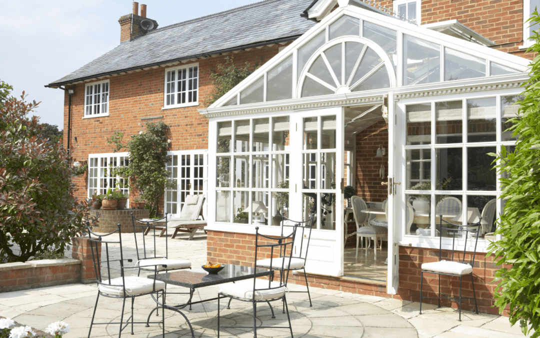 white and glass conservatory on the back of a red brick house